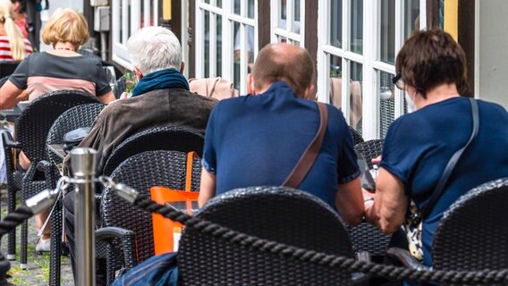 Menschen sitzen in einem Straßencafe. © Picture Alliance / dpa Foto: Julian Stratenschulte