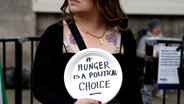 Eine Frau hält bei einer Demonstration ein Schild hoch mit der Aufschrift: "Hunger is a political Choice". © picture alliance / ZUMAPRESS.com | Hesther Ng Foto: Hesther Ng