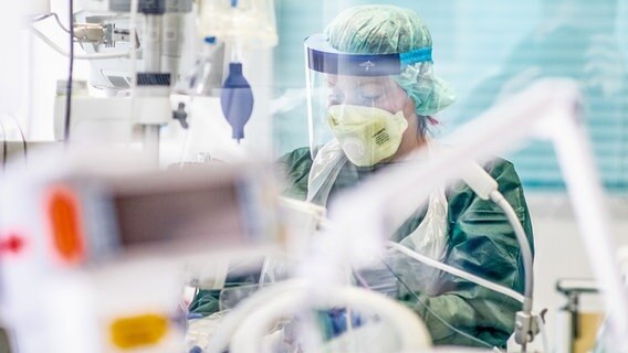 A nurse works in protective clothing in a hospital room in the intensive care unit.  © picture alliance / dpa Photo: Marcel Kusch