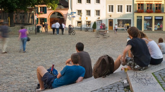 Jugendliche sitzen auf Treppen an einem Platz. © Daniel Schoenen / picture alliance Foto: Daniel Schoenen