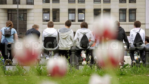 Jugendliche sitzen auf einem Zaun an der Straße. © picture alliance / photothek | Thomas Koehler 