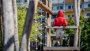 Ein Kind steht auf einem Spielplatz vor einem Plattenbau. © Thomas Eisenhuth / picture alliance Foto: Thomas Eisenhuth