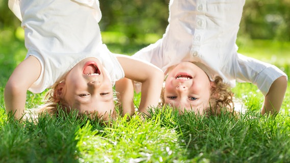 Zwei Mädchen machen auf einer Wiese Kopfstand. © fotolia.com Foto: Igor Yaruta