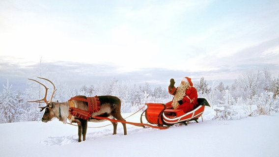 Verkleideter Nikolaus auf seinem Rentierschlitten im tiefverschneiten Lappland. © picture-alliance / dpa Foto: Lehtikuva Oy Kainulainen