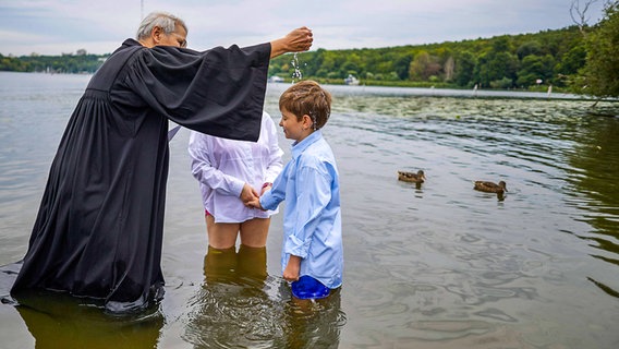 Ein Pastor tauft einen Jungen im See © picture alliance/dpa Foto: Jörg Carstensen