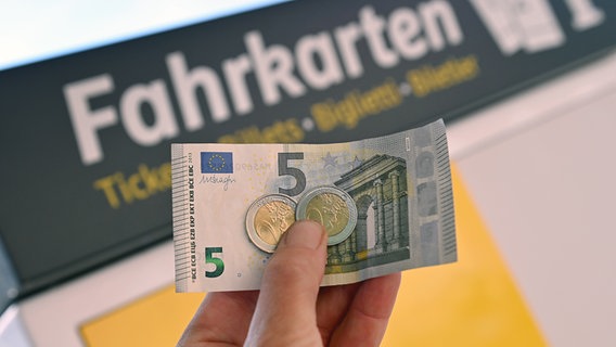 Neun Euro werden vor einen Fahrkartenautomaten in einer Hand gehalten. © picture alliance / SvenSimon Foto: Frank Hoermann/SVEN SIMON
