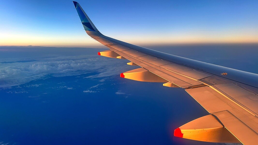 Die Tragfläche eines Flugzeugs vor einem blauen Himmel.