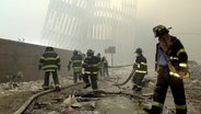 Feuerwehrleute tragen Feuerlöschschläuche zwischen den Trümmern des am 11. September 2001 zerstörten World Trade Centers. © Mark Lennihan/AP/dpa Foto: Mark Lennihan/AP/dpa