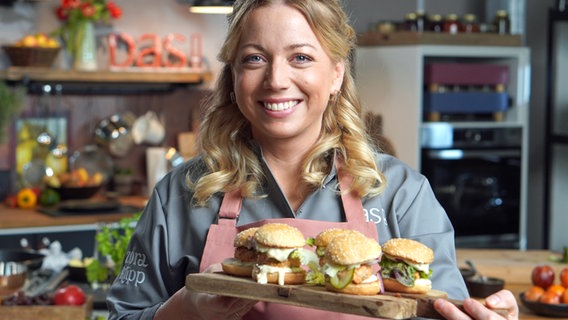 Zora Klipp hält ein Brett mit Burgern in der Hand. © NDR Foto: Florian Kruck