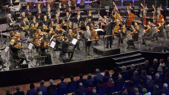 Die NDR Radiophilharmonie auf der Bühne mit dem Bariton Christian Gerhaher spielt auf einer Bühne. © NDR Screenshot 