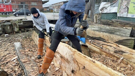 Zwei Frauen arbeiten mit Äxten an einem Baumstamm. © NDR Foto: Frank Hajasch