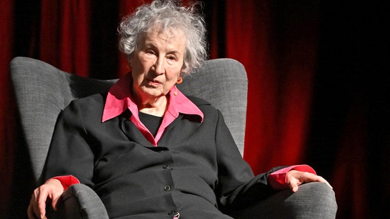 Eine ältere Frau mit weißen Haaren und roter Bluse sitzt in einem Sessel und schaut aufmerksam: Margaret Atwood, kanadische Schriftstellerin im November 2024 © Imago/TT Jonas Ekströmer/TT Foto: Jonas Ekströmer