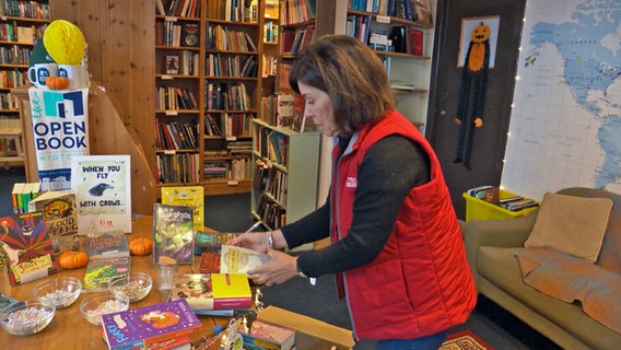 Eine Frau sortiert Bücher in einem Laden, dahinter sind Bücherregale mit Büchern - auch über Schottland. © NDR Screenshot Foto: Franziska Hoppen