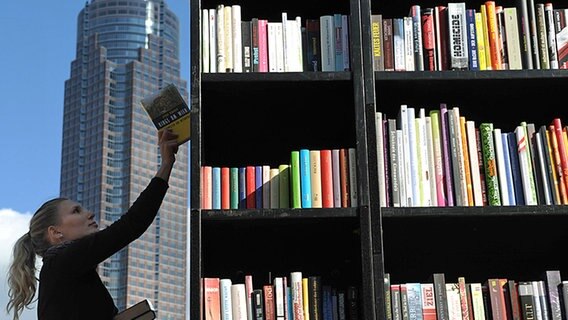 Eine Frau steht vor einem Regal mit bunten Buchrücken. © picture-alliance/dpa Foto: Arne Dedert