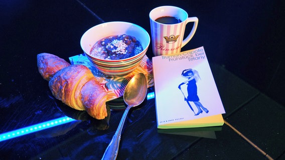 Ein Frühstück mit Croissant neben einem Buch - Folge 44 von eat.READ.sleep © NDR Foto: Tim Piotraschke