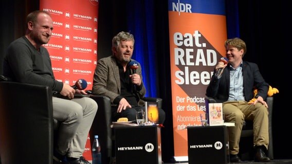 Die Hosts von eat.READ.sleep Daniel Kaiser (links), Jan Ehlert (rechts) mit Schriftsteller Matthijs Deen in Buchholz auf der Bühne der "Empore" © NDR Foto: Patricia Batlle