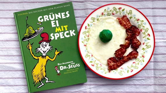 Ein Buch mit dem Titel "Grünes Ei mit Speck" liegt neben einem Teller mit eben dem Inhalt - eat.READ.sleep Folge 27 © NDR Foto: Katharina Mahrenholtz