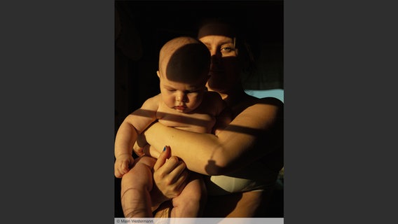 Eine Frau hält ein Baby in die Kamera; Bild von Malin Westermann aus: "Eye Mama", teNeues Verlag © Malin Westermann 