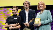 Die Illustratorin Regina Kehn und der Autor Sasa Stanisic nehmen den Jugendliteraturpreis für ihr Kinderbuch "Wolf" entgegen. Rechts steht Bundesfamilienministerin Lisa Paus. © picture alliance/dpa | Boris Roessler Foto: picture alliance/dpa | Boris Roessler