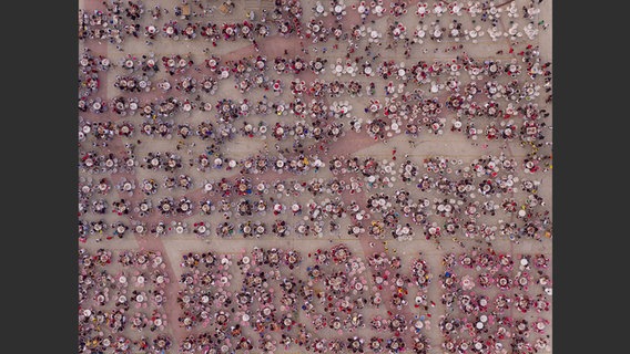 Abbildung aus dem Bildband "Feed the Planet": Luftaufnahme von sehr vielen Menschen, die an runden Tischen essen © George Steinmetz/Knesebeck Verlag Foto: George Steinmetz