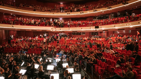Ränge mit roten Sitzen in einem Opernhaus, auf denen Publikum sitzt. © Dutch National Opera 