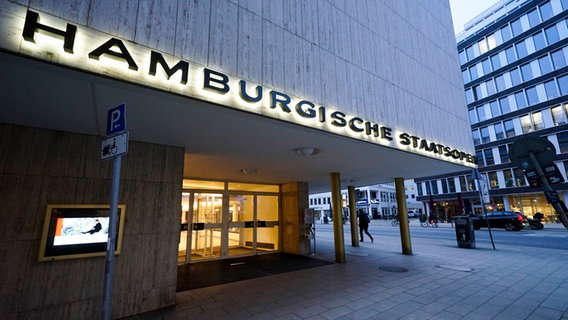 Ein graues Haus mit dem Schriftzug: Hamburger Staatsoper. © picture alliance / ABBfoto 