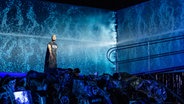 Szene aus "Satyagraha": Ein Mann steht vor einem blauen Hintergrund © Staatsoper Hannover/ Sandra Then Foto: Sandra Then