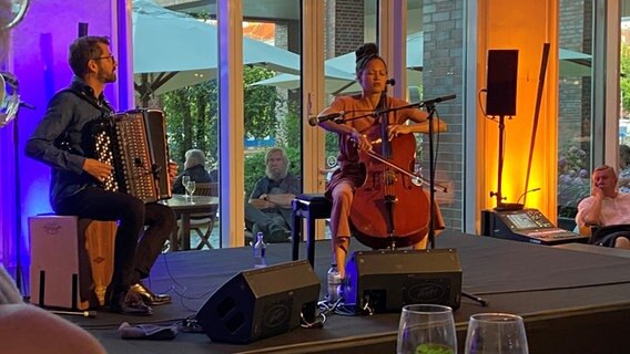 Ein Mann sitzt auf einer Bühne und spielt Akkordeon, rechts neben ihm sitzt eine Frau und spielt Cello. © Linda Ebener / NDR Foto: Linda Ebener