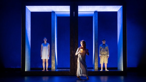 Neima Fischer (Flora), Mélanie Boisvert (Gouvernante), Elias Nickel (Miles) auf einer blau beleuchteten Bühne in Schlafanzügen und Nachthemden in der Oper "The Turn of the Screw" am Oldenburgischen Staatstheater © Oldenburgisches Staatstheater Foto: Stephan Walzl