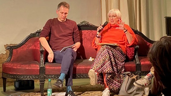 Kulturstaatsministerin Claudia Roth sitzt mit dem Grünen-Abgeordneten Sven-Christian Kindler auf einem roten Sofa © NDR / Andrea Schwyzer 