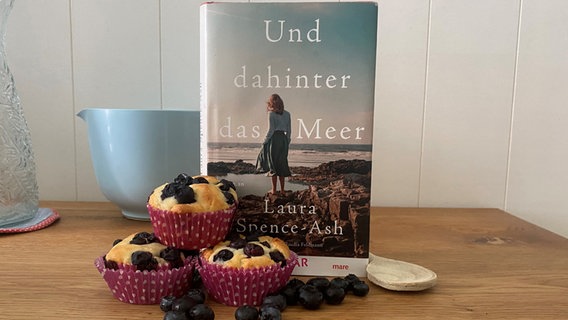 Vor einem Buch stehen Blaubeer-Muffins © Katharina Mahrenholz Foto: Katharina Mahrenholz