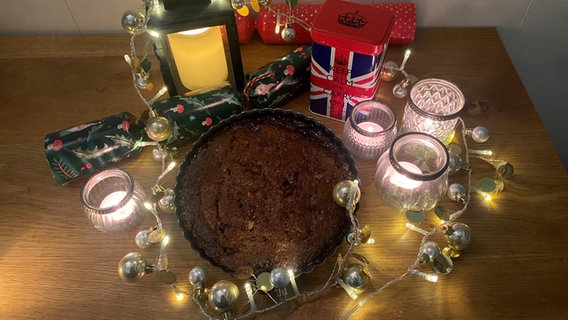 Ein Kuchen steht auf einem Tisch, umrahmt von einer Lichterkette © NDR Foto: Katharina Mahrenholtz