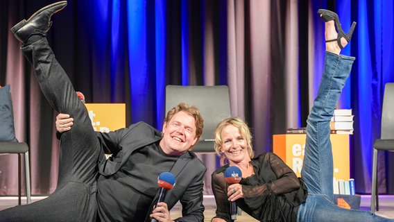 Jan Ehlert und Katharina Mahrenholtz liegen auf dem Boden und strecken ein Bein gen Himmel. © NDR 