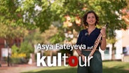 Die Saxophonistin Asya Fateyeva steht mit ihrem Instrument in einem Park und lächelt in die Kamera. © NDR 