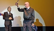 Ein Mann im dunklen Anzug mit Brille auf dem roten Teppich beim Filmfest Hamburg © NDR Foto: Patricia Batlle