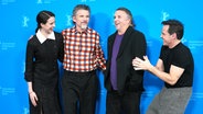 eine junge Frau und drei Männer, einer davon im karierten Hemd, scherzen vor einer Fotostellwand der Berlinale (das Filmteam zu "Blue Moon" von Regisseur Richard Linklater) © Sören Stache/dpa +++ dpa-Bildfunk +++ Foto: Sören Stache