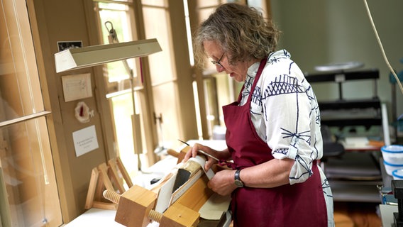 Eine Buchrestauratorin arbeitet an einem beschädigten Exemplar aus der verbrannten Anna Amalia Bibliothek © Klassik Stiftung Weimar 