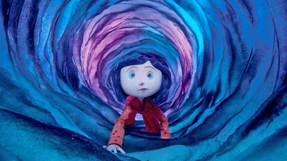 Ein blauhaariges Mädchen schaut böse, wie eine Frau mit Knöpfen statt Augen etwas verspeist - Szene aus "Coraline" © Trafalgar Releasing 