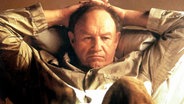 Gene Hackman verschränkt die Arme hinter dem Kopf © picture alliance / Everett Collection | ©Paramount/Courtesy Everett Collection 