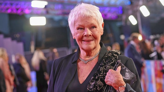 Eine ältere Frau mit kurzen weißen Haaren lächelt bei einer Filmpremiere - Dame Judi Dench, britische Schauspielerin, bei einer Premiere auf dem roten Teppich © x 