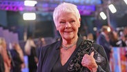 Eine ältere Frau mit kurzen weißen Haaren lächelt bei einer Filmpremiere - Dame Judi Dench, britische Schauspielerin, bei einer Premiere auf dem roten Teppich © x 