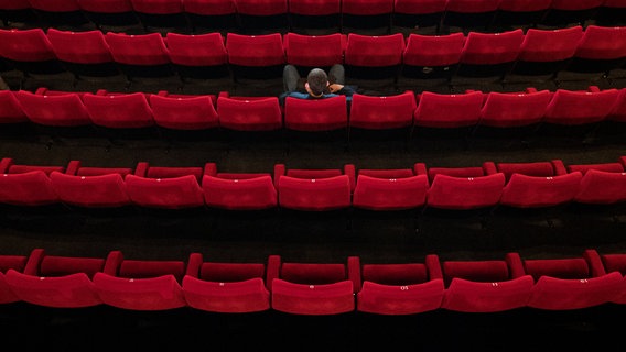 A single viewer sits in an empty cinema with red velvet armchairs © Daniel Reinhardt / dpa bildfunk 