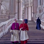 Zwei Geistliche unterhalten sich auf den Treppen des Vatikans miteinander - Szene aus Edward Bergers Film "Konklave" mit Ralph Fiennes © Leonine 