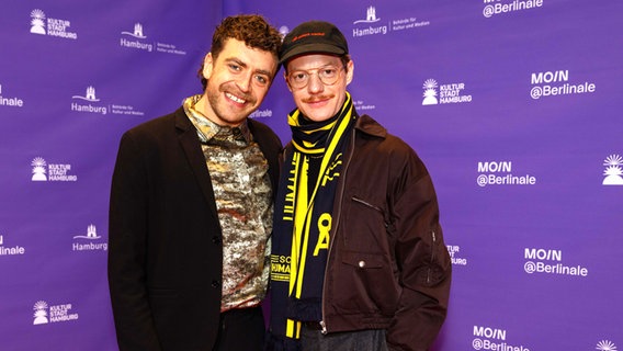 Zwei junge Männer in dunklen Outfits lächeln beim Empfang der Moin Filmförderung der Berlinale © Jasper Ehrich / Florian Arp Foto: Jasper Ehrich / Florian Arp