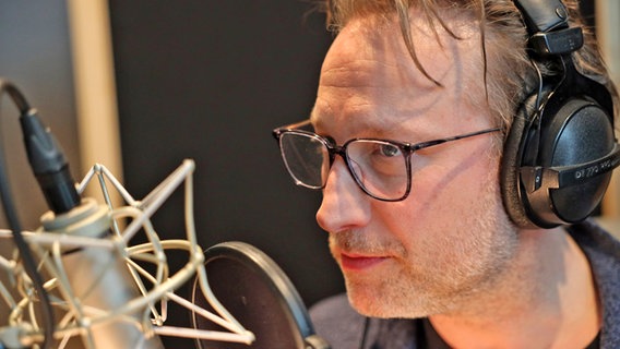 Ein Mann mit Brille spricht in ein Studio-Mikrofon - Der Schauspieler und Synchronsprecher Sascha Rotermund im Studio von NDR Kultur © NDR 