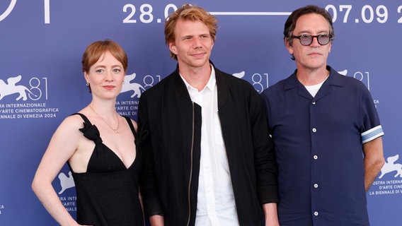 Schauspielerin Leonie Benesch im schwarzen Kleid, Regisseur Tim Fehlbaum (mitte) und Schauspieler Ben Chaplin (r.) beim Filmfest Venedig beim Photocall zum Film "September 5" © picture alliance / Geisler-Fotopress Foto: Uwe Geisler