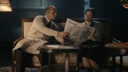Eine Frau und ein Mann sitzen auf einem Sofa und lesen Zeitung © Kinescope Film 