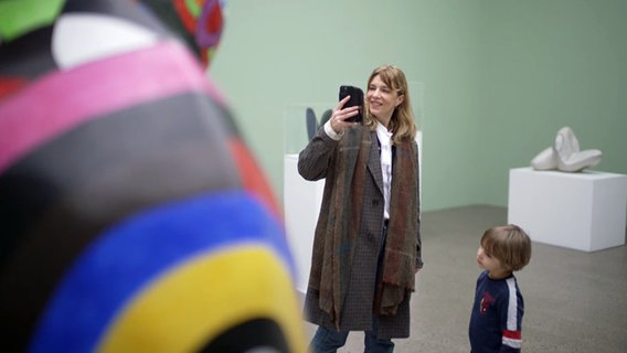 Eine Frau mittleren Alters fotografiert im Museum eine Figur von Nikki de Saint Phalle mit dem Handy © NDR.de 