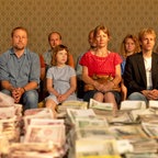 Viele Menschen sitzen vor alten Geldscheinen auf einem Tisch - Szene aus dem Kinofilm "Zwei zu eins" © X-Verleih / Peter Hartwig Foto: Peter Hartwig