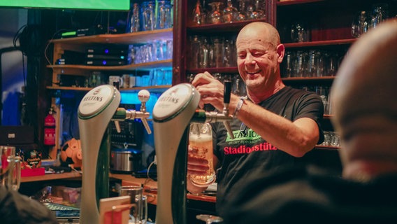 In einer Kneipe zapft ein lächelnder Wirt ein Bier. © NDR Foto: Max von Schwartz